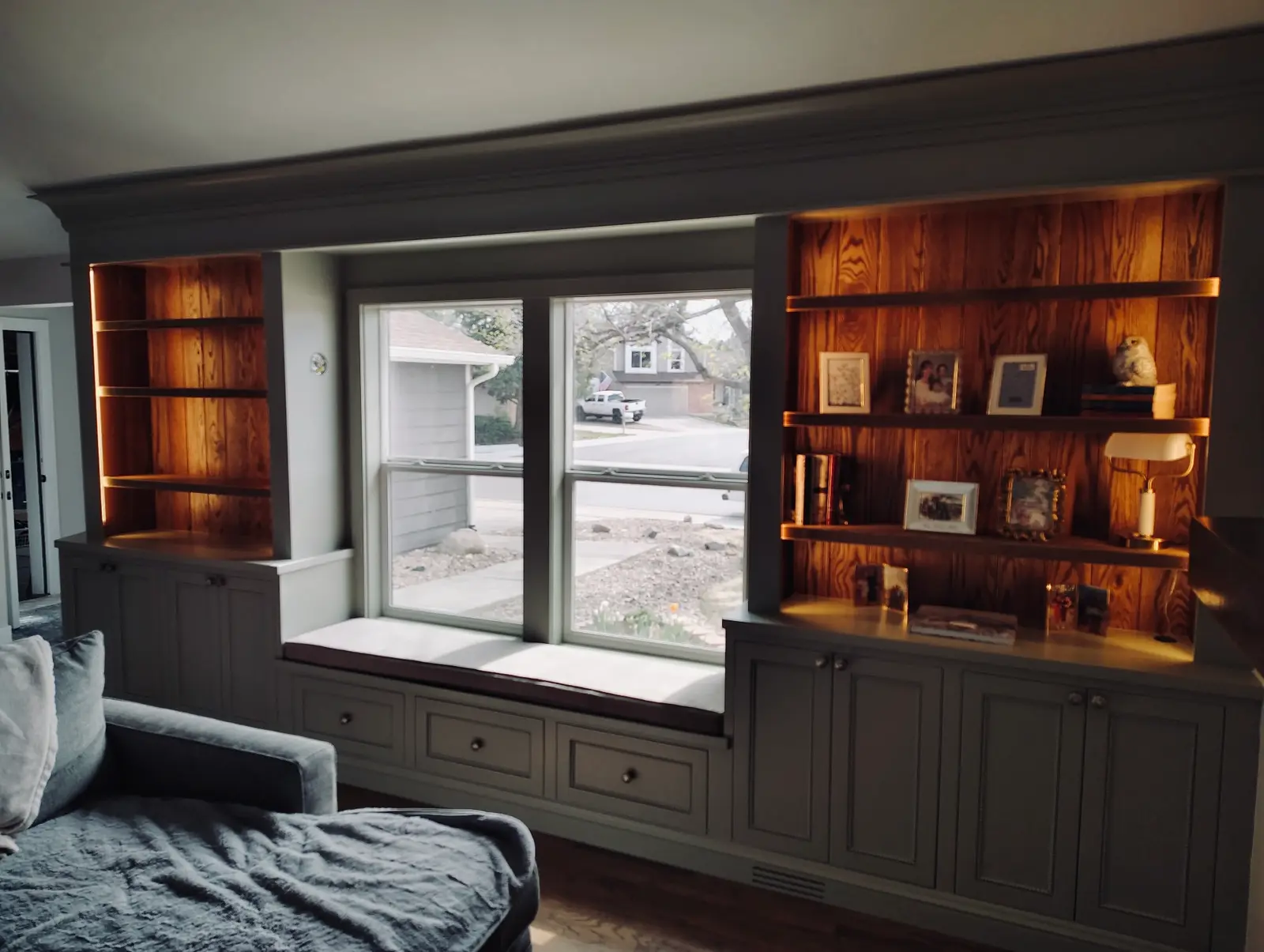Built-in window seat flanked by lit bookshelves and lower cabinets in a living room