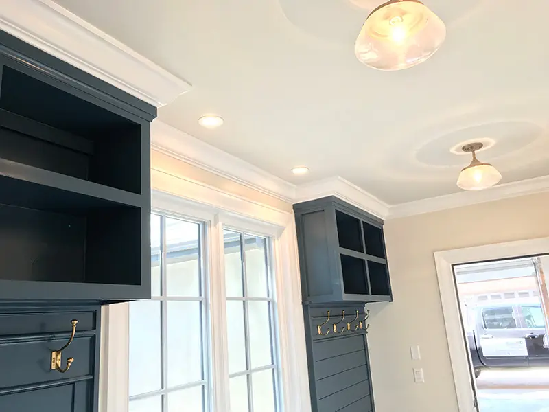 Dark painted built-in shelving and cabinets in a bright room