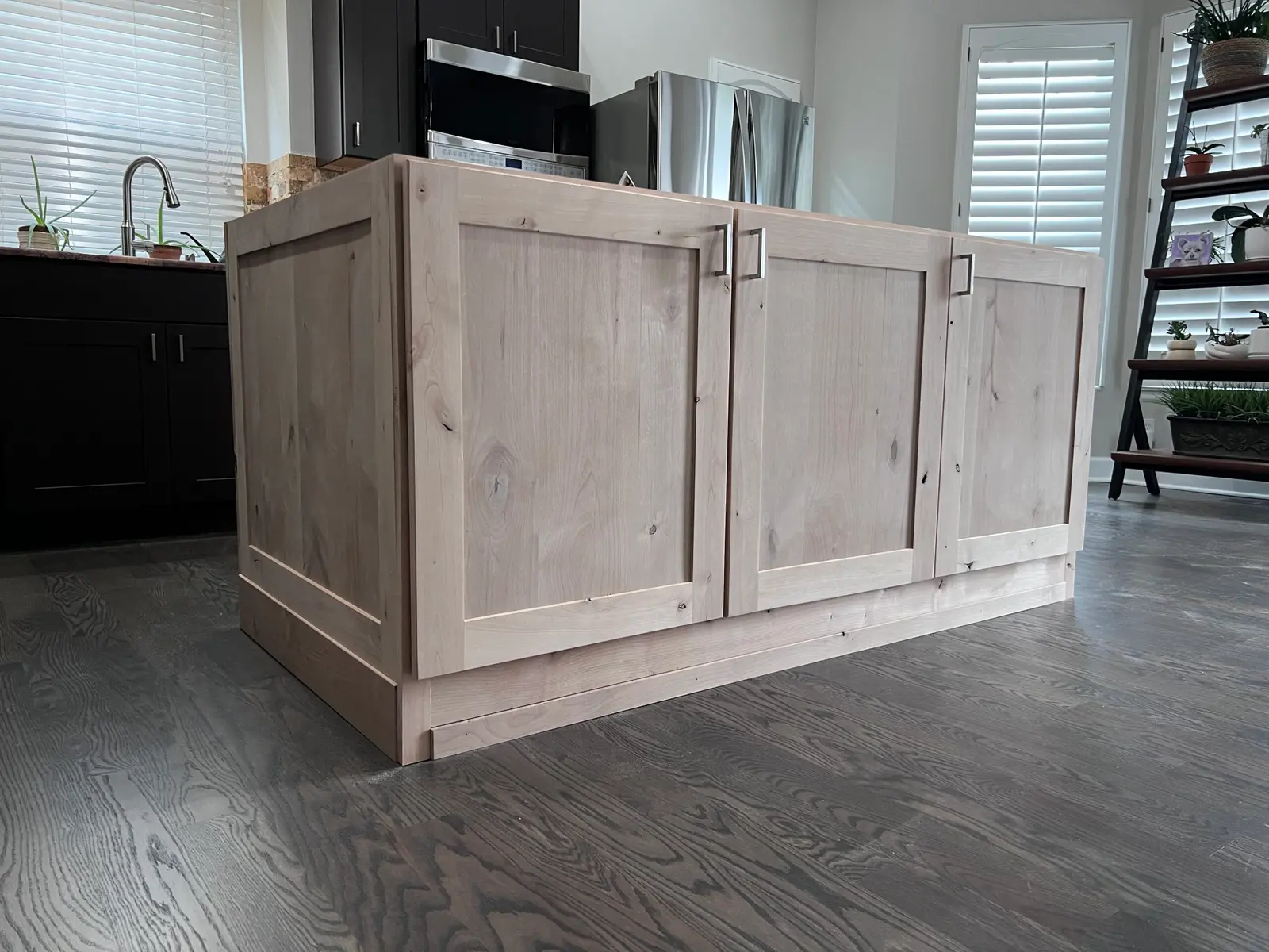 Kitchen island wrapped in light wood raised panels