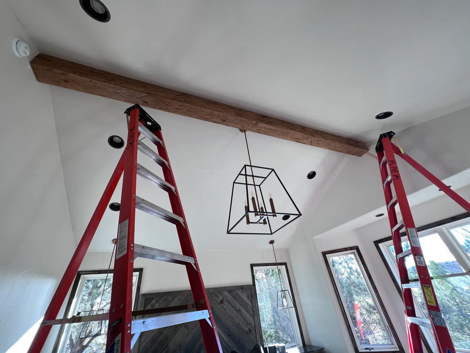 Faux beam being set on a vaulted ceiling between two ladders