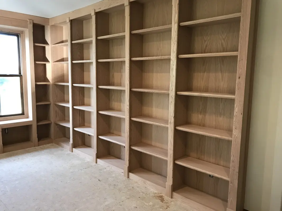 Floor-to-ceiling unfinished wood bookshelves along two walls