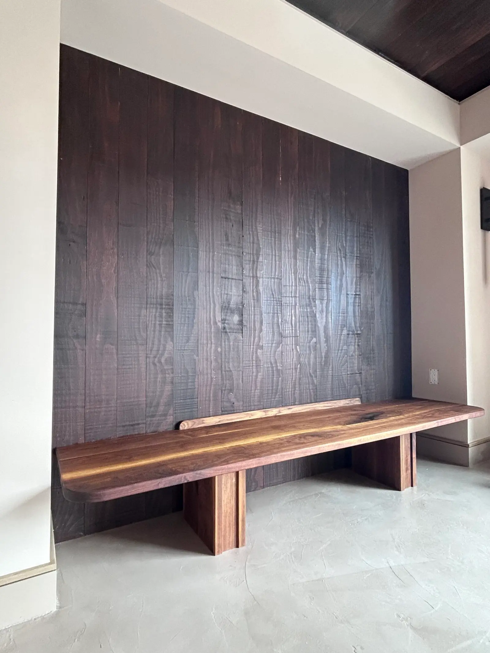 Dark wood paneled wall above a wood bench base