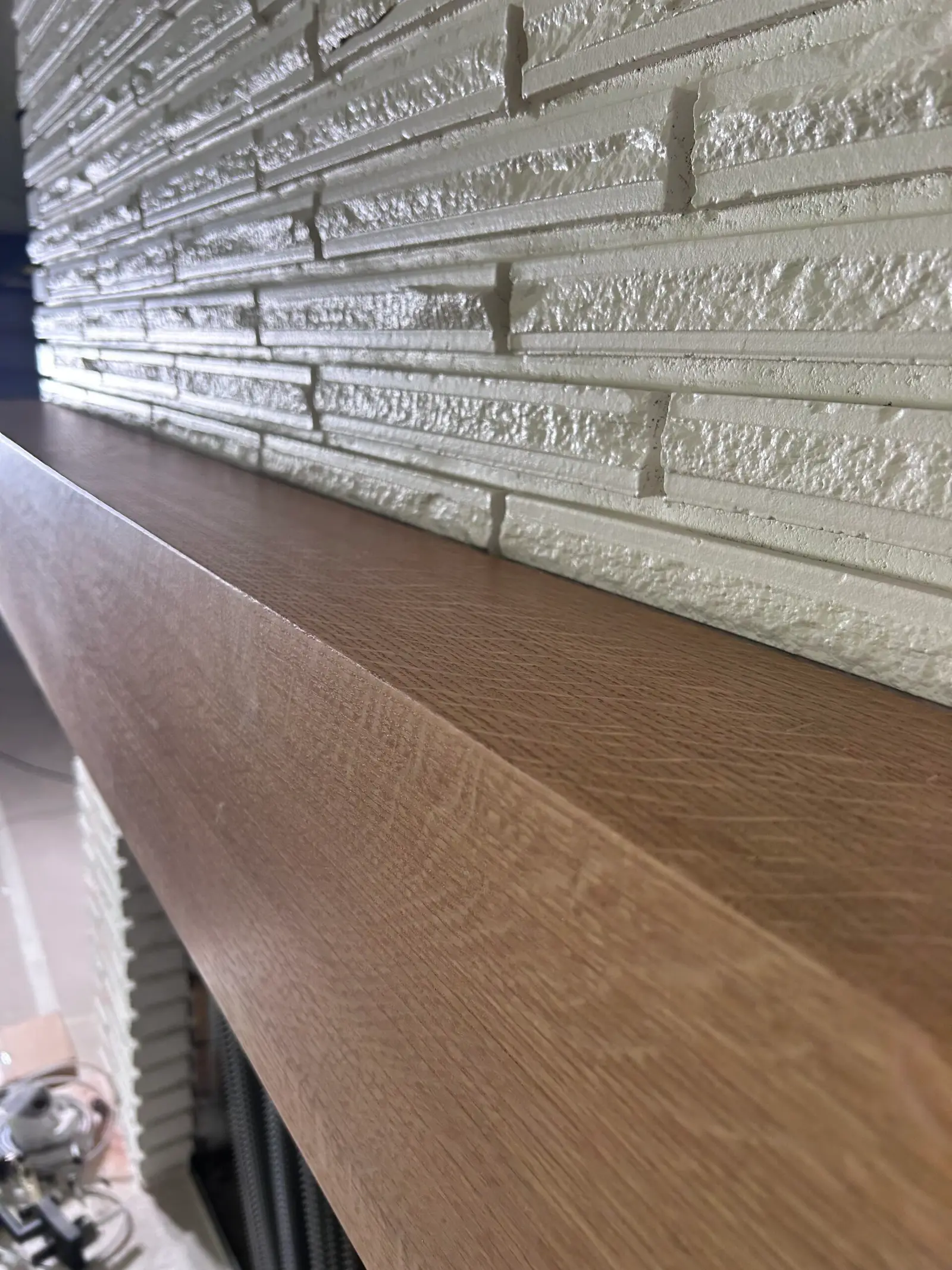 Close-up of a wood mantel edge on white stacked stone