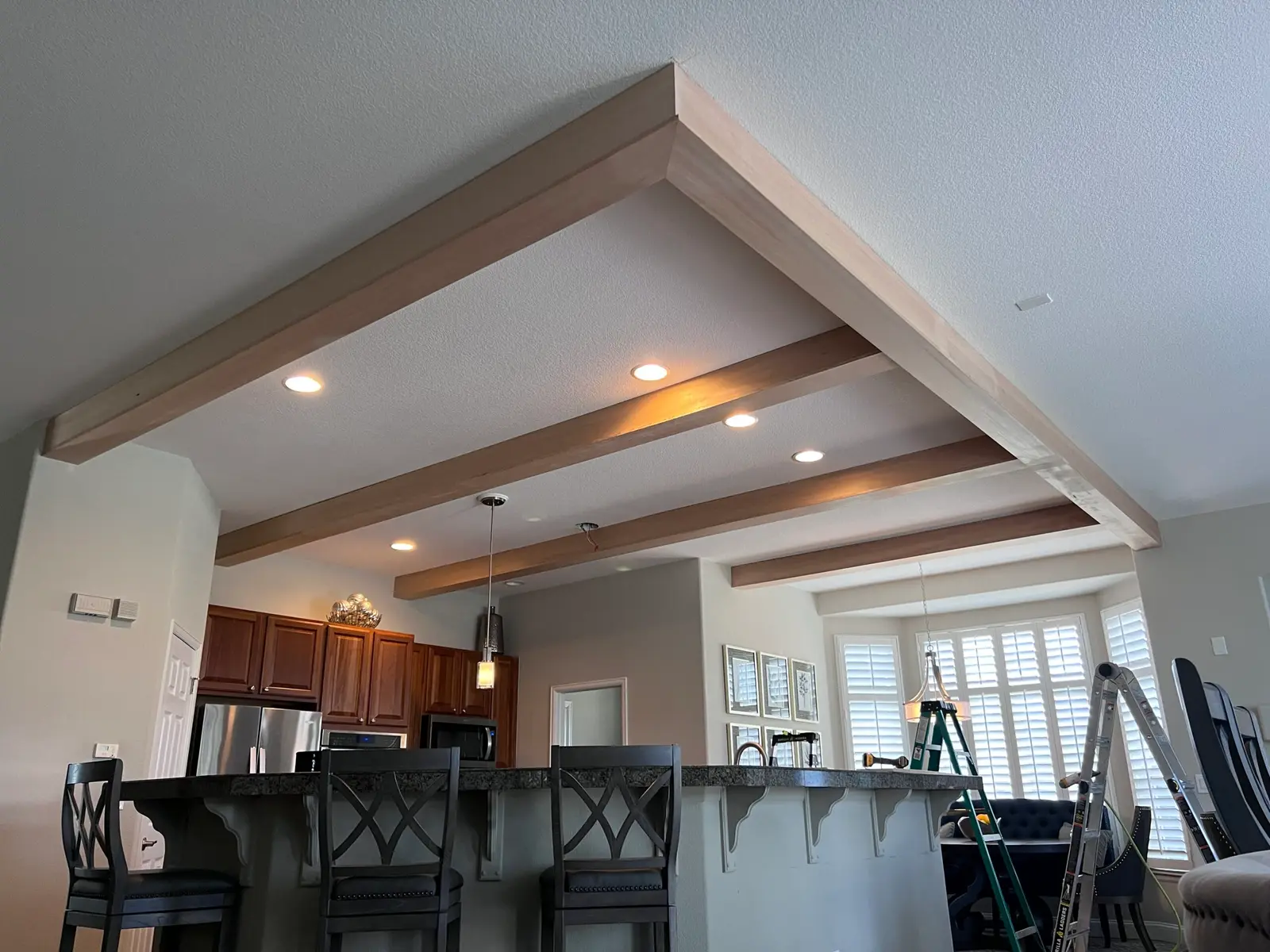 Painted ceiling beams and soffit framing over an open kitchen