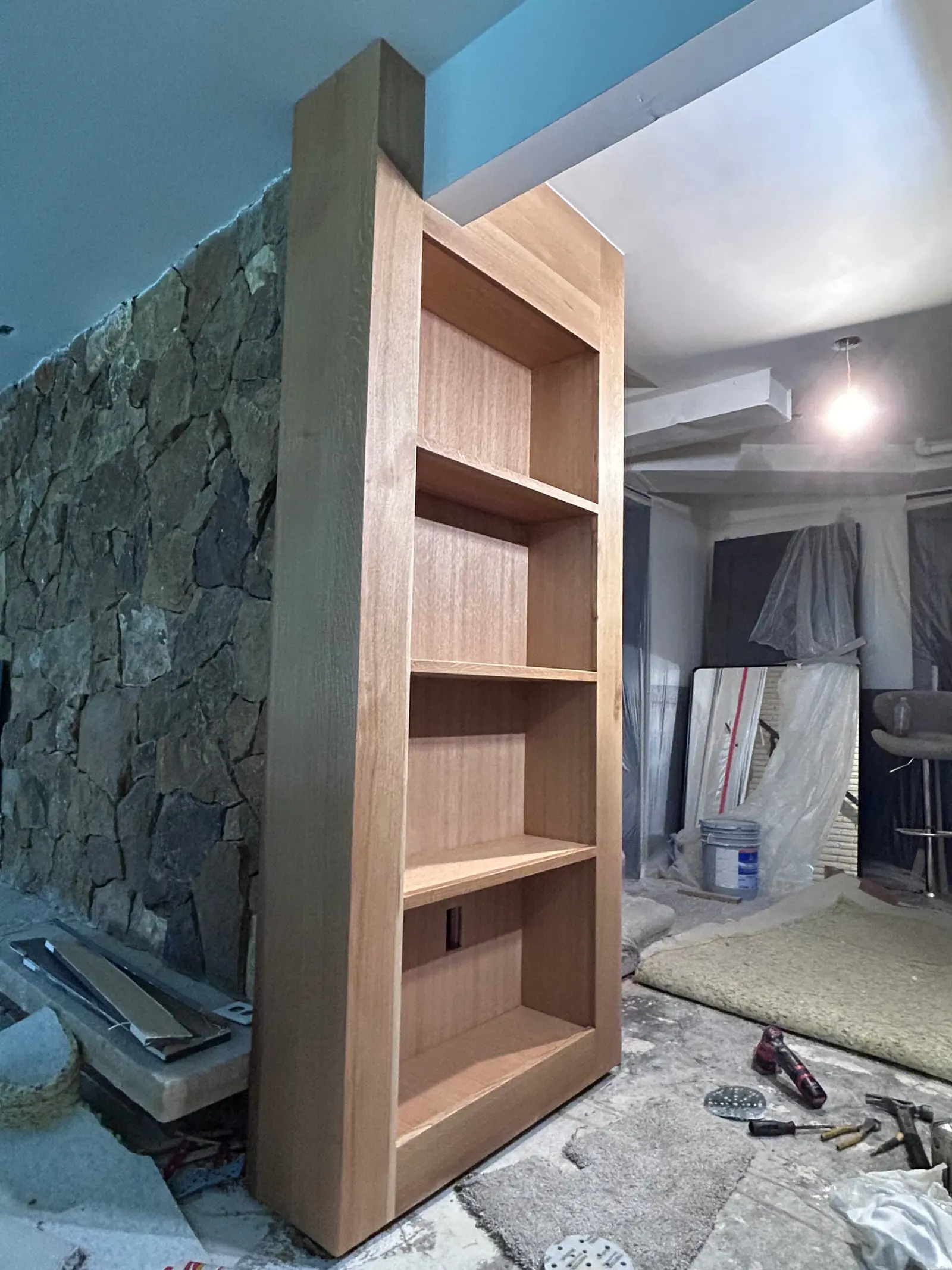 Wood bookcase built into a stone wall during installation