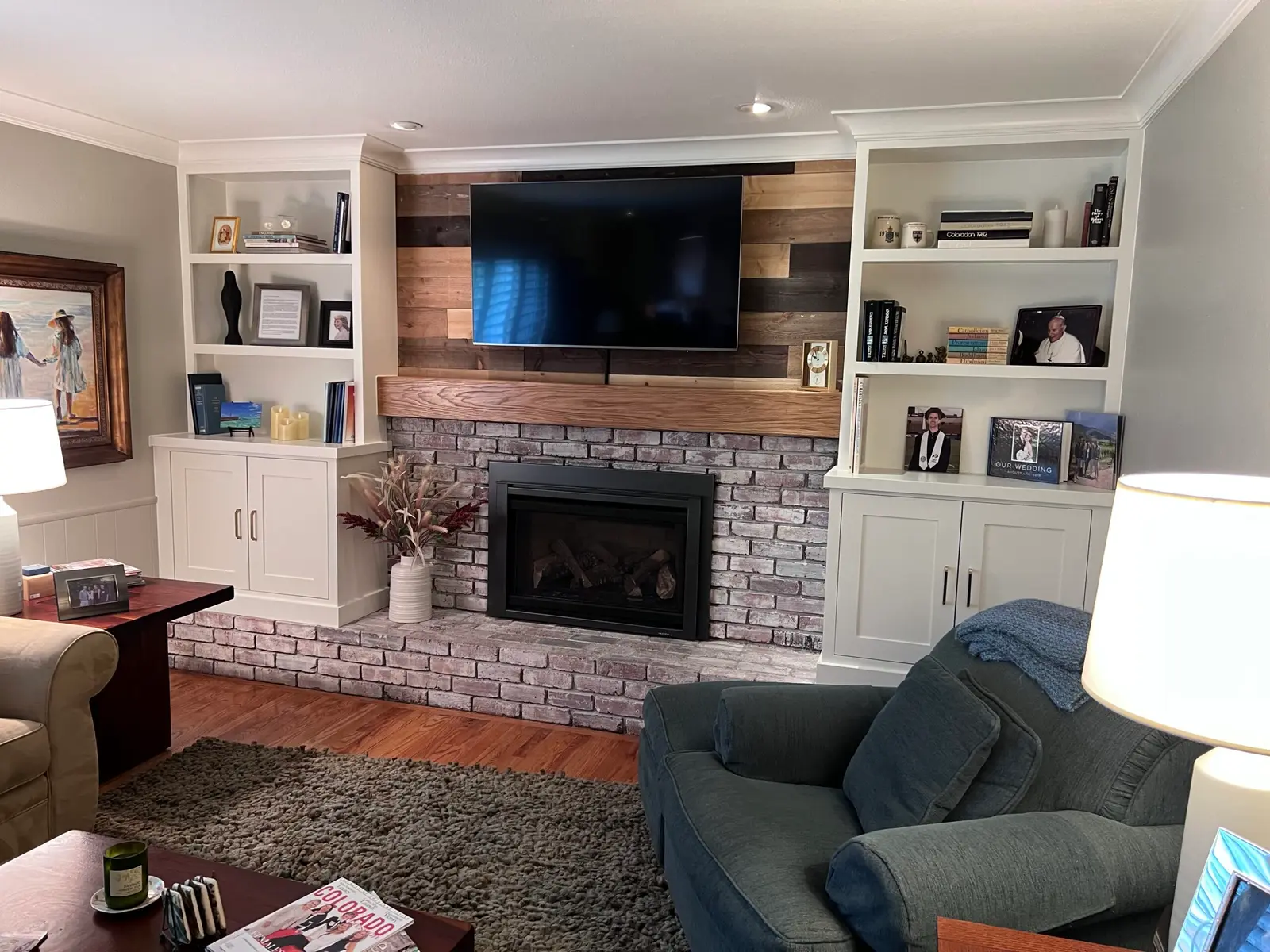 Living room with white built-ins on both sides of a wood plank accent wall and brick fireplace