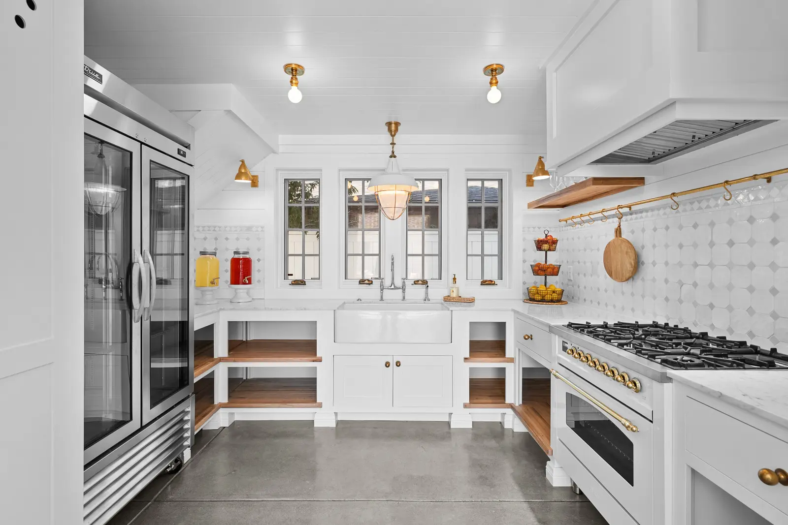 White kitchen with open wood shelving, a range wall and a glass-front refrigerator