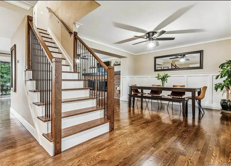 Staircase with wood treads and iron balusters rising from a dining room