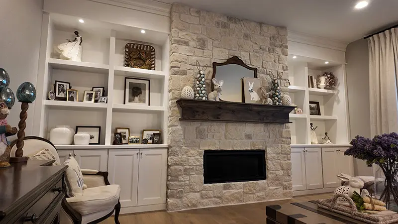 Stone fireplace with a dark mantel framed by white built-in bookcases